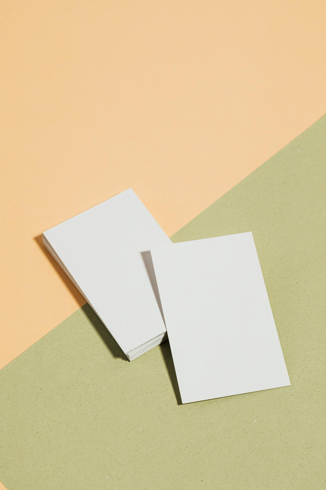 A stack of blank business cards laid on a pastel colored surface, perfect for corporate presentations.